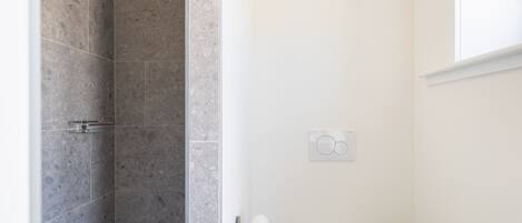 A bathroom with a shower, toilet, and a radiator.