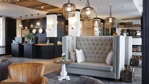 A modern lobby with a tufted sofa, wooden accents, and wicker pendant lighting. - West Bay (Middelkerke)