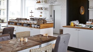 A modern kitchen with wooden ceiling beams, white cabinets, and a central island with seating. - West Bay (Middelkerke)