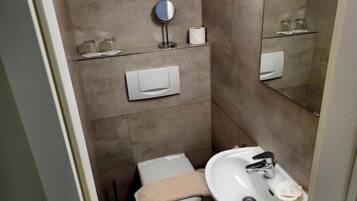 A compact bathroom with a toilet, sink, and a mirror.