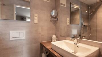 A modern bathroom with two sinks, a large mirror, and a shower.
