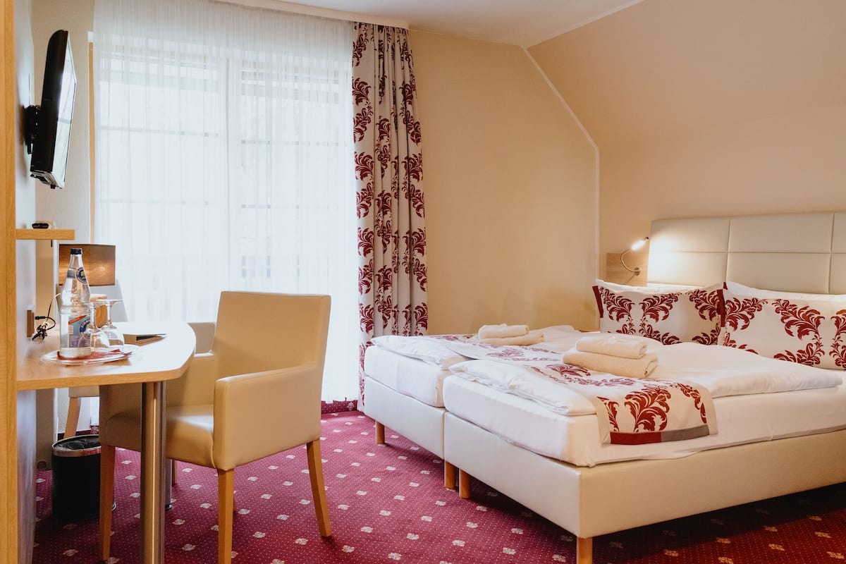 Una habitación de hotel con cama, escritorio, silla y televisor montado en la pared.