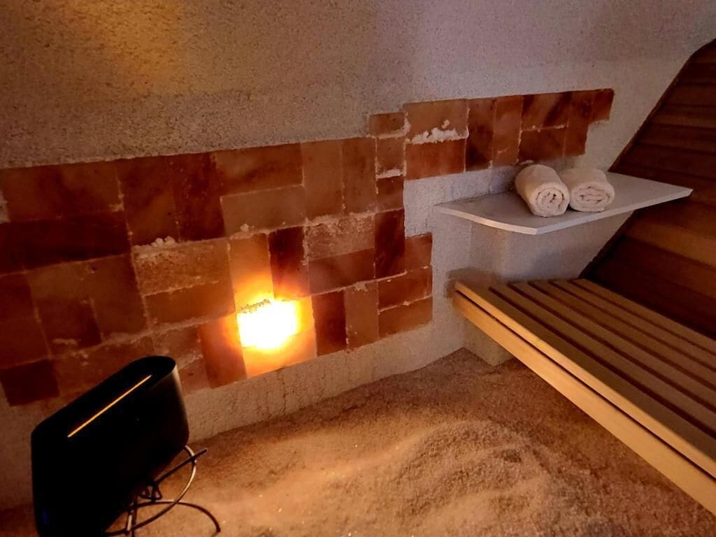 A room with a brick fireplace, a wooden bench, and a shelf with towels.