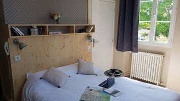 A neatly made bed with pillows, a bedside lamp, and a laptop on a wooden headboard.