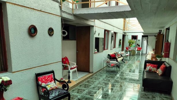 A spacious indoor area with a high ceiling, tiled floor, and a mix of seating arrangements including a sofa and chairs. - Hotel Angamos (Santiago)