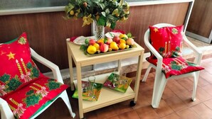 A small table with a fruit arrangement, a vase with green leaves, and a tray with glasses. - Hotel Angamos (Santiago)