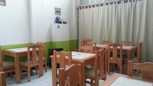 A room with wooden tables and chairs, a whiteboard, and a window with curtains. - Hotel Angamos (Santiago)