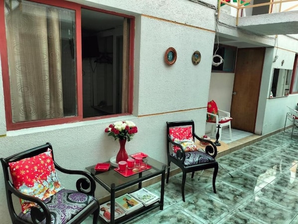 A room with two chairs, a small table, and a window with curtains. - Hotel Angamos (Santiago)