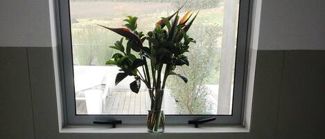 Un baño con ventana, bañera y una pequeña planta en maceta.