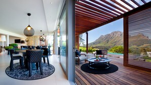 A modern interior with a dining area, a seating area with a view, and a wooden deck. - Clouds Estate (Stellenbosch)
