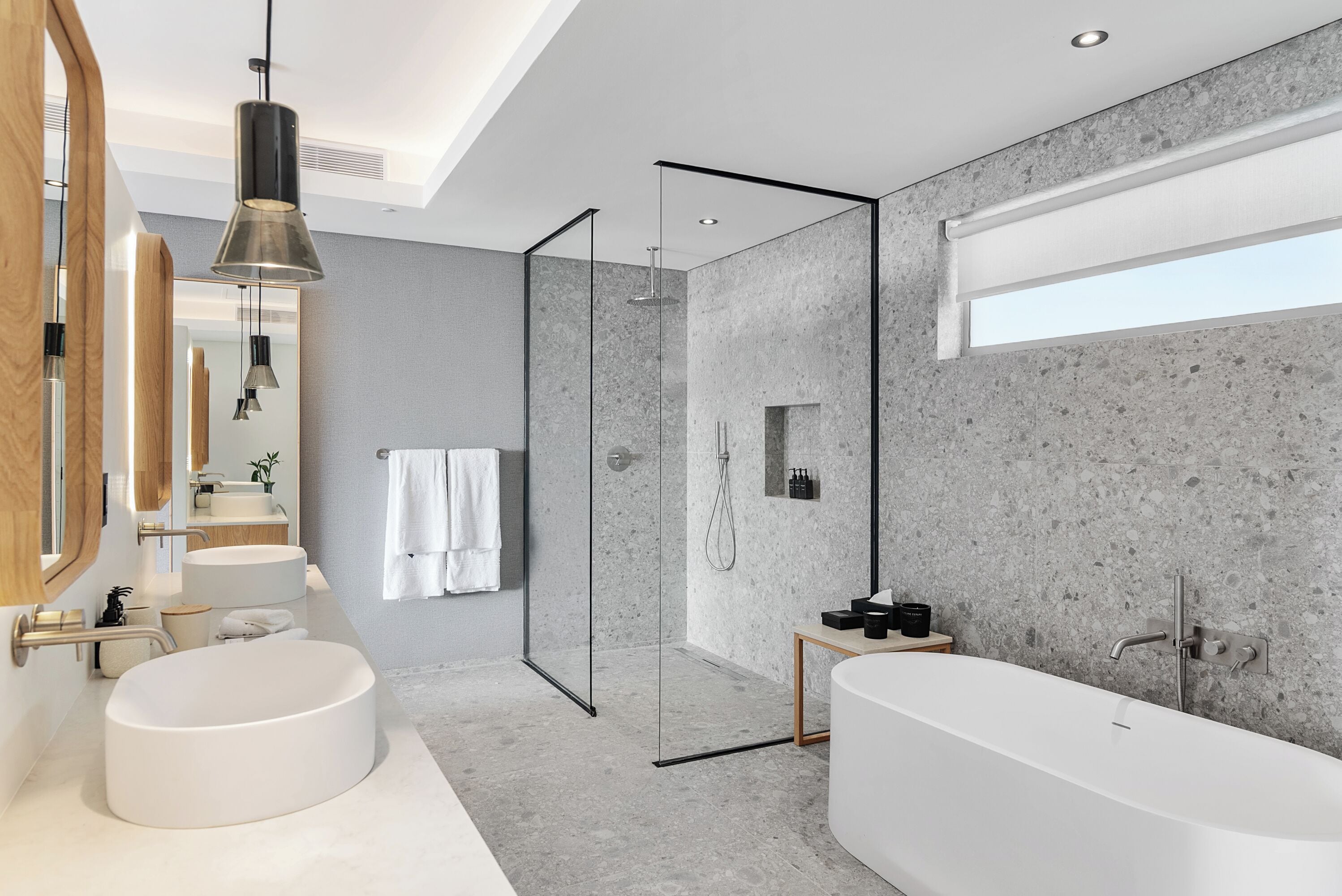 A modern bathroom with a freestanding bathtub, a glass-enclosed shower, and a large mirror.
