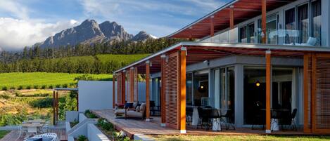 Une maison moderne dotée d’une terrasse, d’un espace salon extérieur et offrant une vue sur les montagnes.