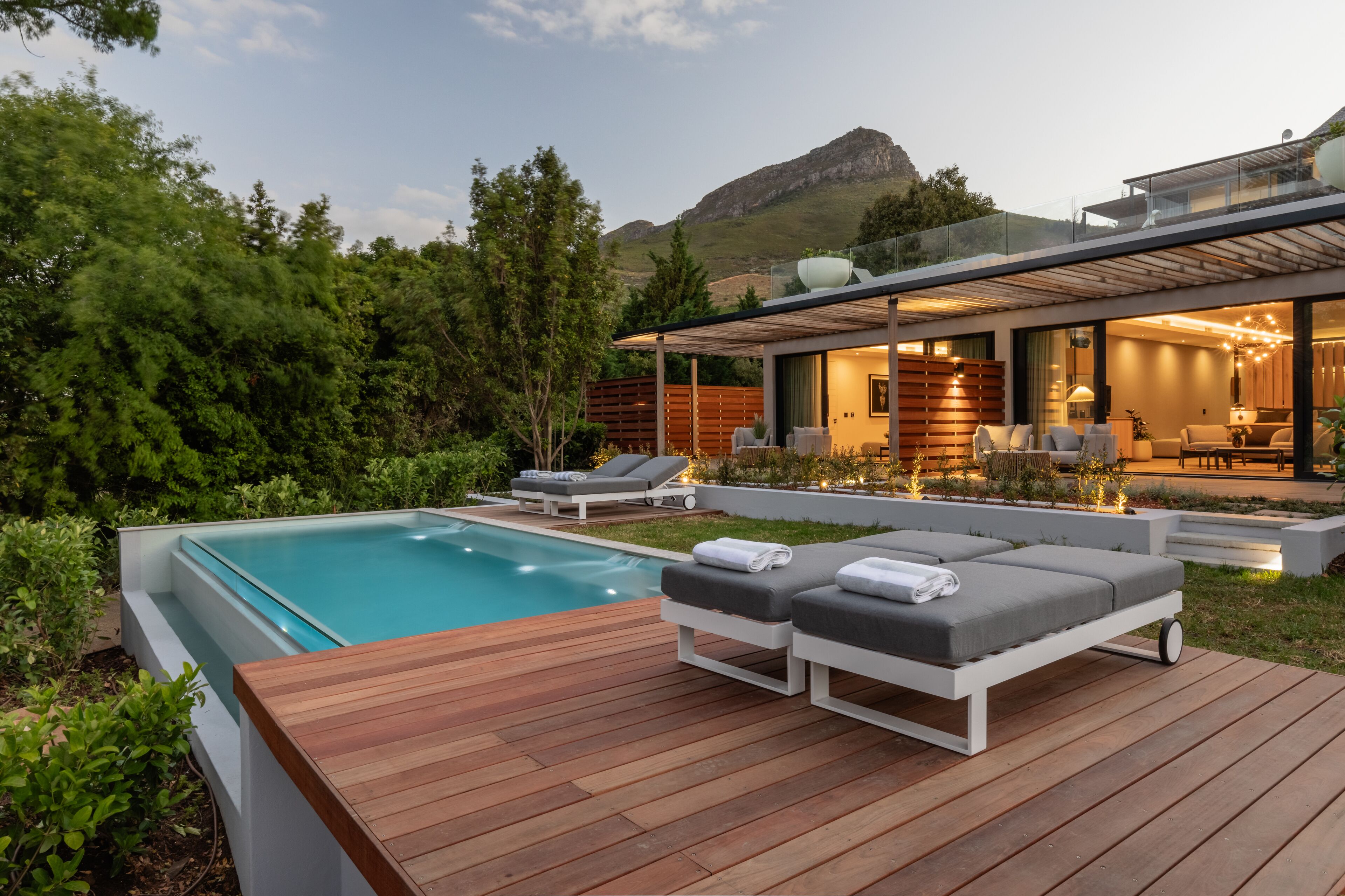 A modern house with a swimming pool, outdoor seating, and a view of the mountains.