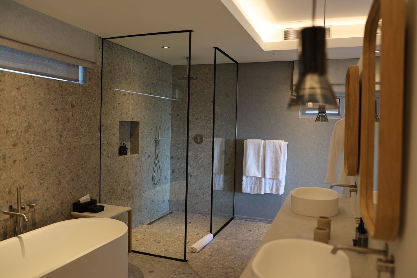 A modern bathroom with a large bathtub, a separate shower area, and a vanity with a mirror.