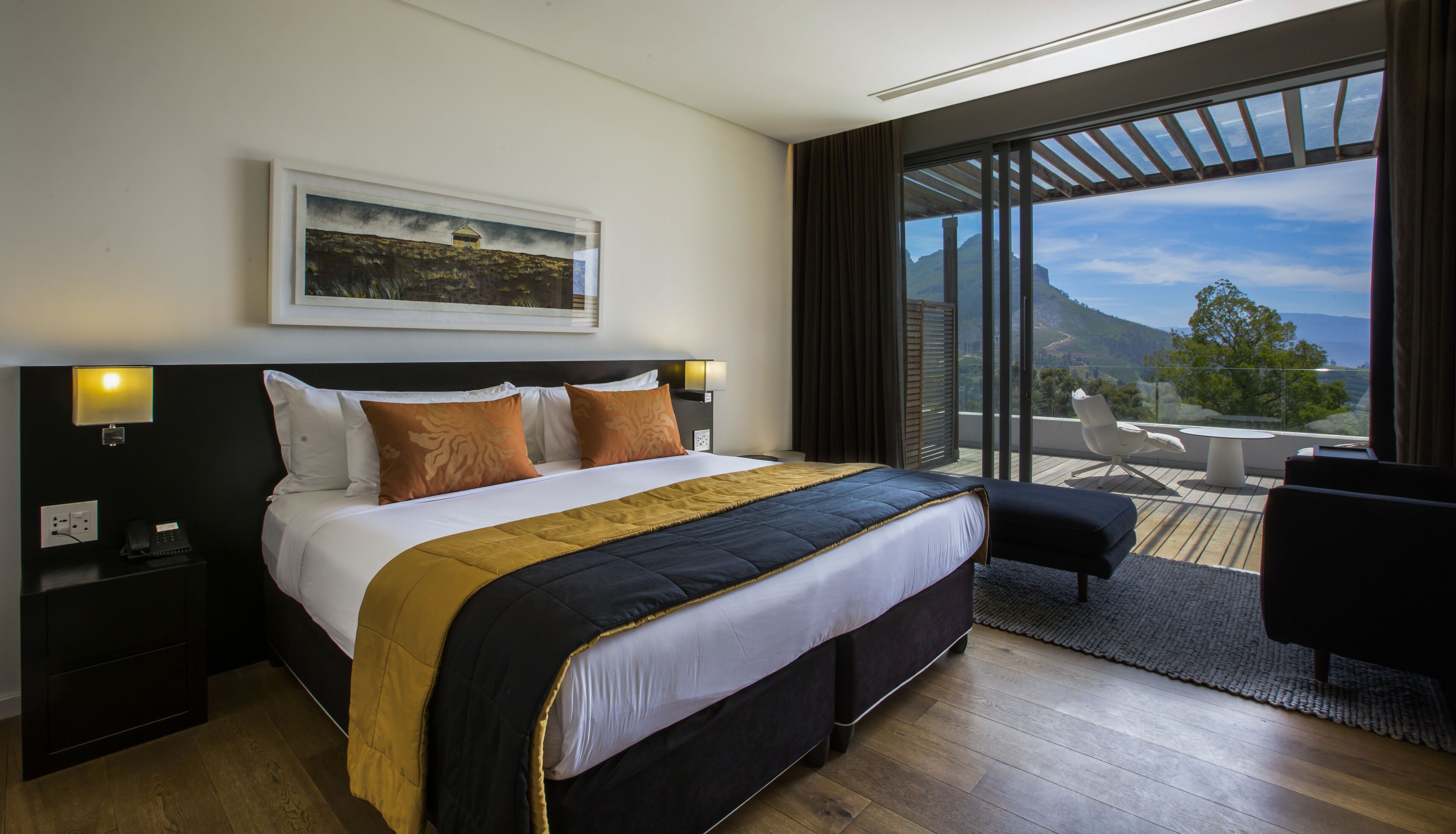 A hotel room with a large bed, a desk, and a view of the mountains through the window.