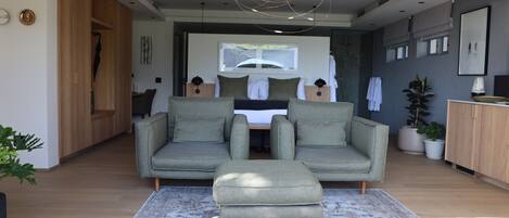 A modern living room with a grey sofa set, a matching ottoman, and a patterned rug.