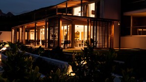 A modern house with a covered patio, large windows, and outdoor seating. - Clouds Estate (Stellenbosch)