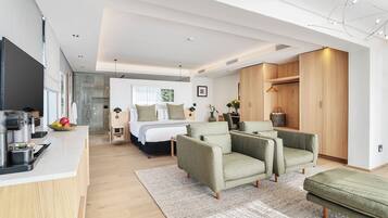 A modern, well-lit room with a kitchen, a dining area, and a seating area with sofas.