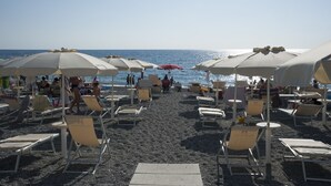 A beach with rows of sun loungers and umbrellas, some occupied by people. - San Domenico Family Hotel (Scalea)
