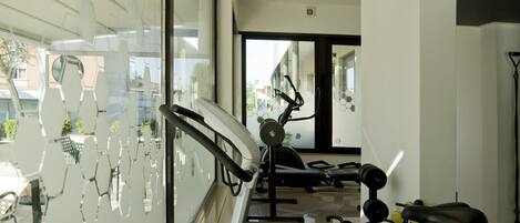 Un gimnasio moderno con equipo de ejercicio, un ventanal y vistas al exterior.