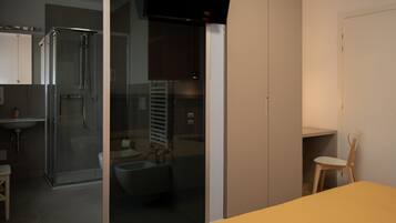 A modern bathroom with a glass shower enclosure, a toilet, and a sink.