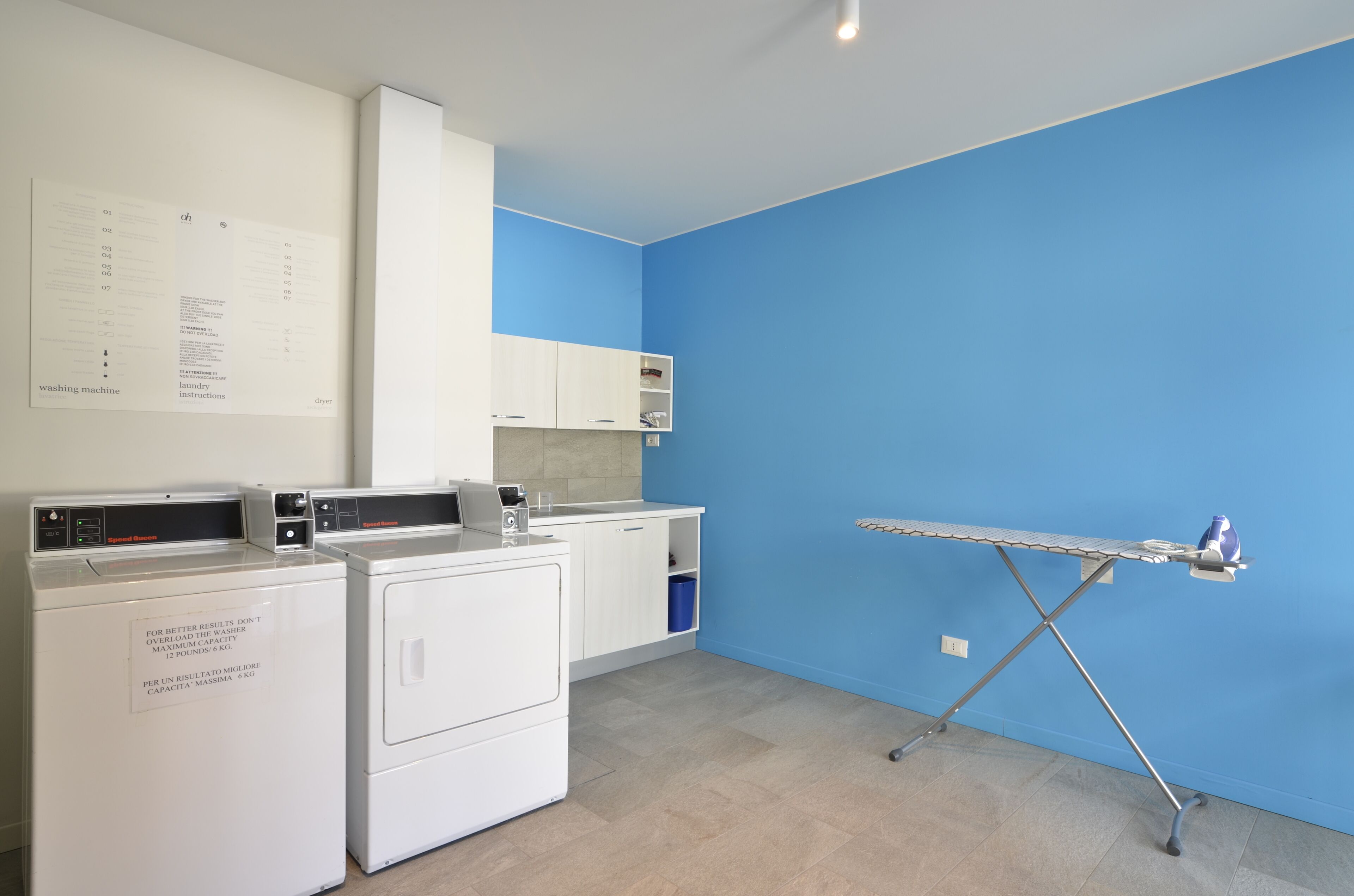 A laundry room with a blue wall, a drying rack, and stacked laundry baskets.