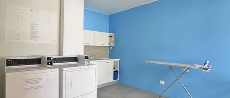 A laundry room with a blue wall, a drying rack, and stacked laundry baskets.