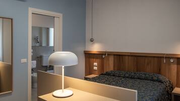 A bedroom with a bed, bedside table, lamp, and a wooden headboard.