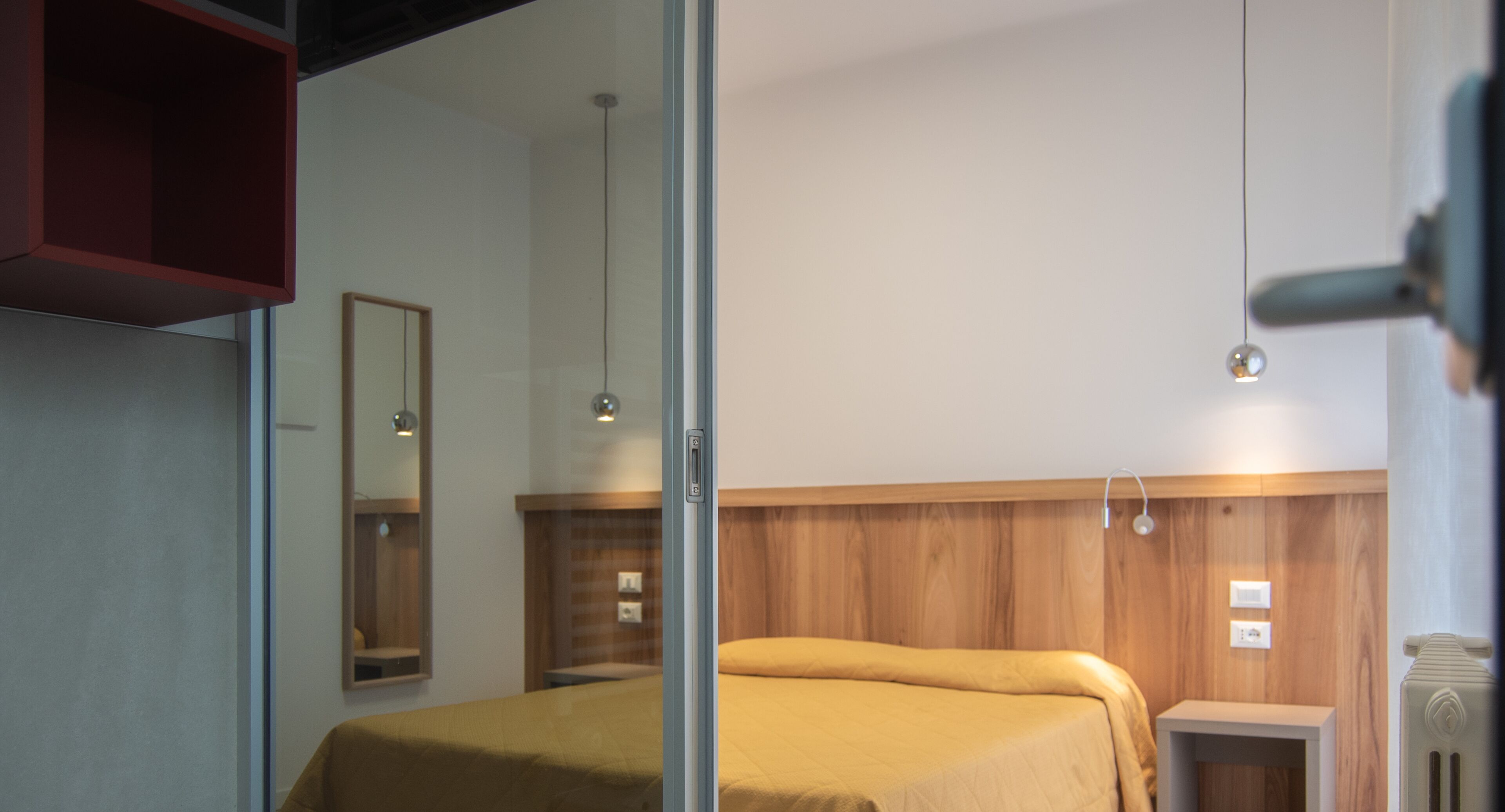 Un dormitorio moderno con cabecera de madera, cama con colcha amarilla, mesita de noche y espejo en la pared.