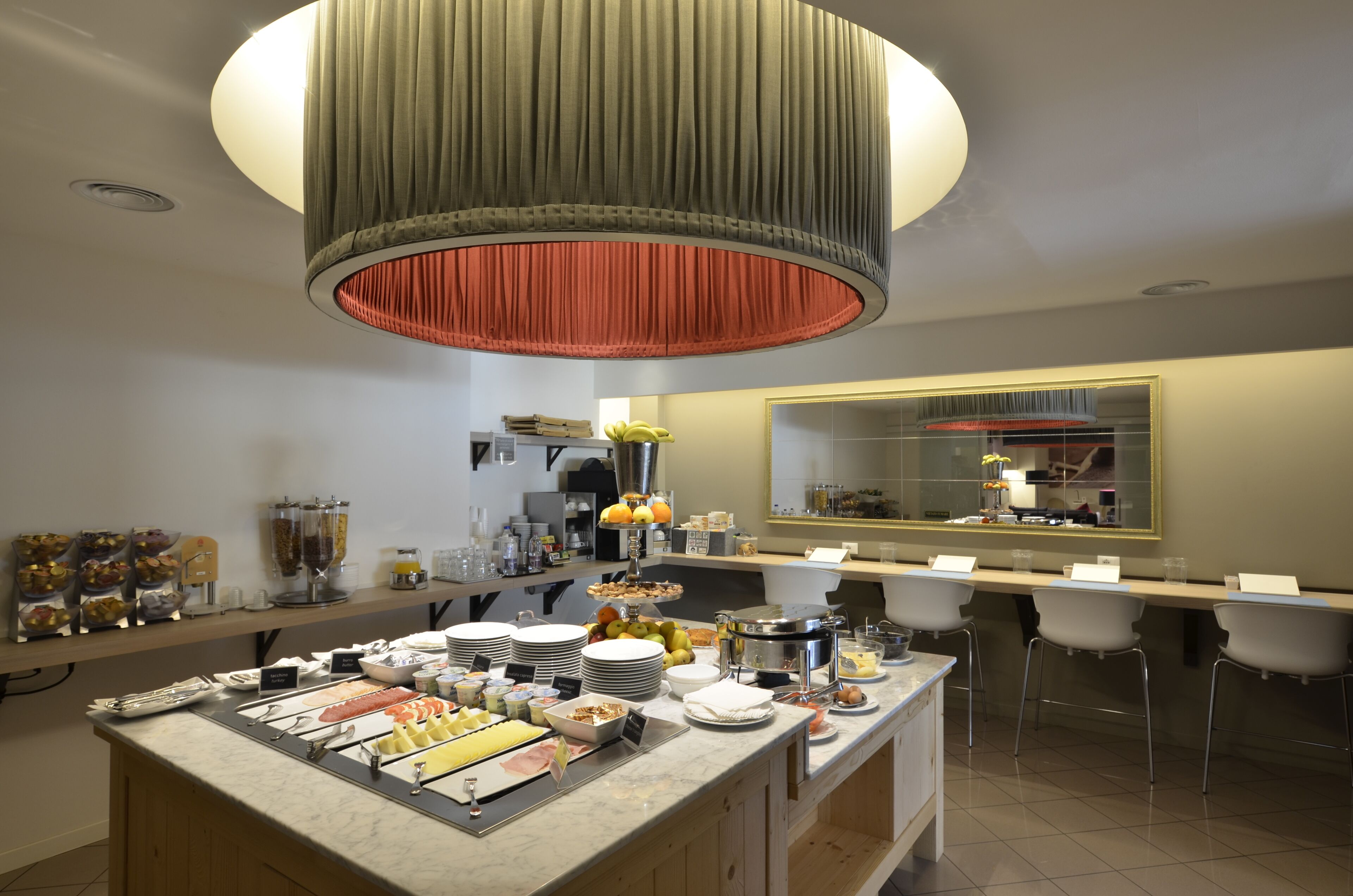 A modern kitchen with a central island, bar stools, and a large mirror.