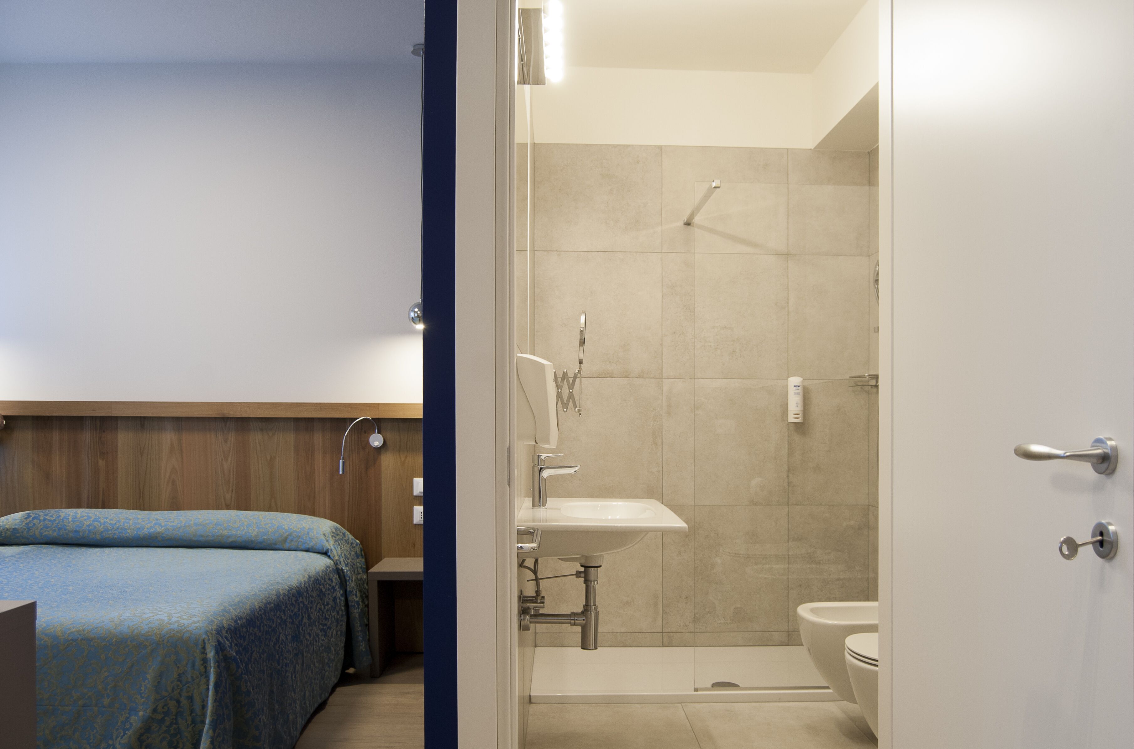 Habitación de hotel con cama, baño completo con ducha, lavamanos e inodoro.