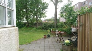 A garden with a paved patio, potted plants, a wooden bench, and a statue. - Alba Guesthouse (Reykjavik)