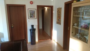 A hallway with wooden doors, a black vase, a framed photo, and a glass cabinet with tea sets.