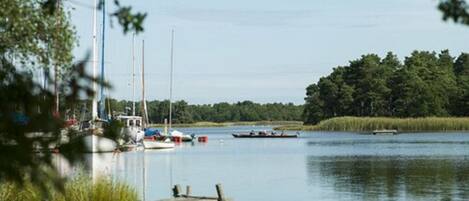 A calm lake with boats, a dock, and a forested area in the background.