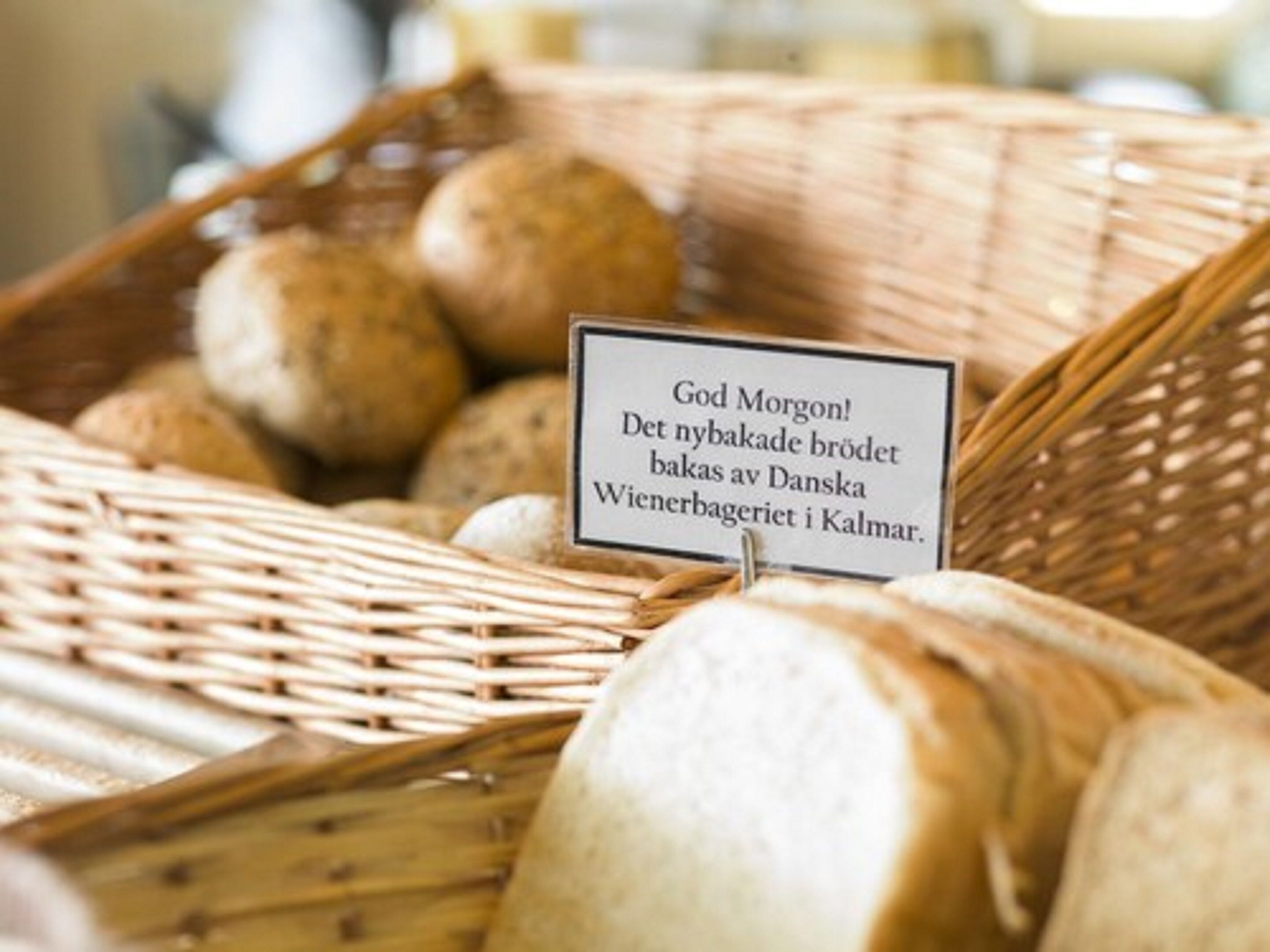 A wicker basket filled with bread and a sign with text in a foreign language.