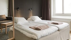 Un dormitorio moderno con dos camas, una mesita de noche, una lámpara y una ventana con cortinas.