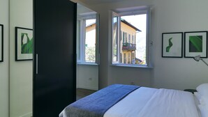 Een slaapkamer met een bed, een kast en een raam met uitzicht op een gebouw.