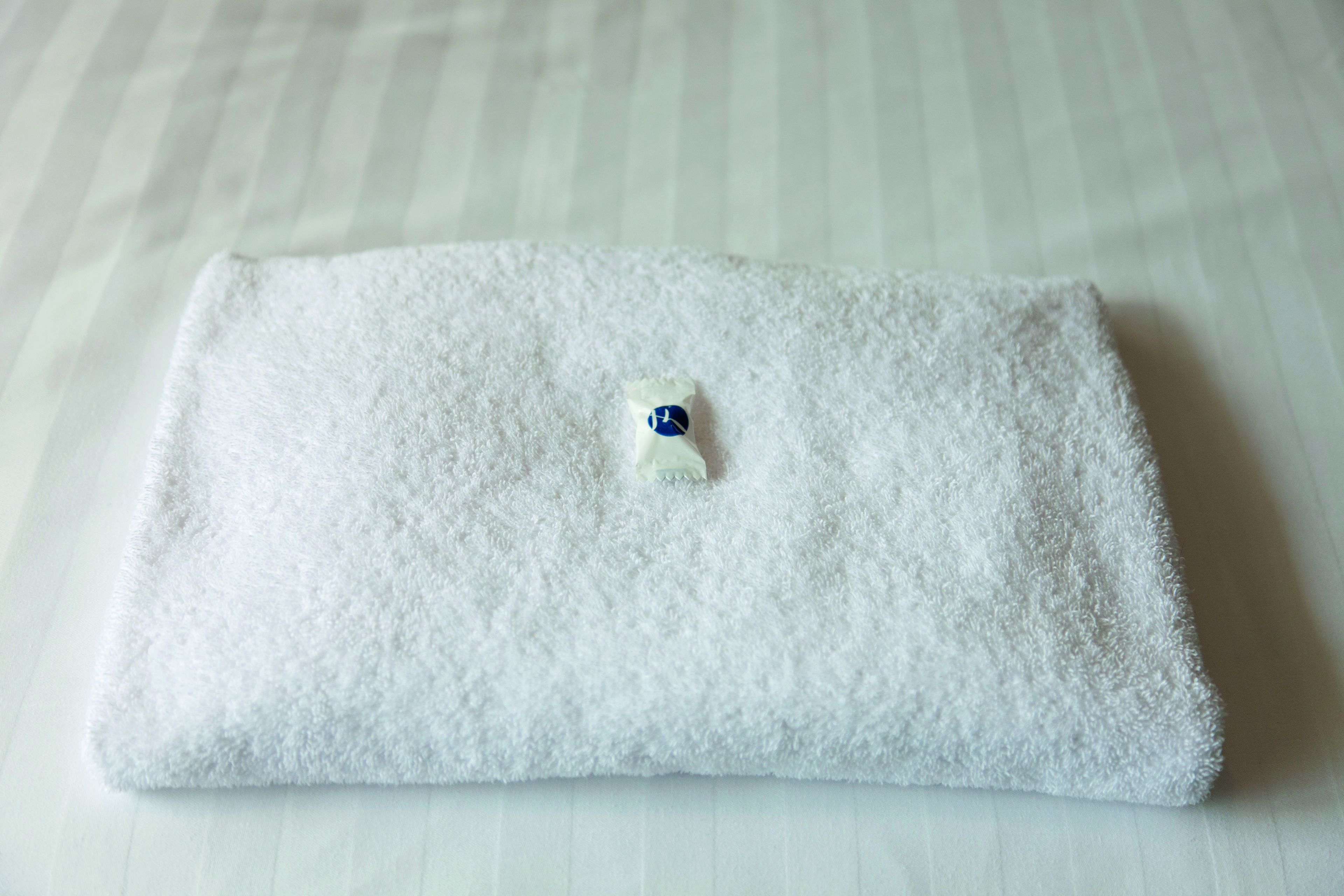 Una toalla blanca doblada sobre una cama con estampado a rayas.