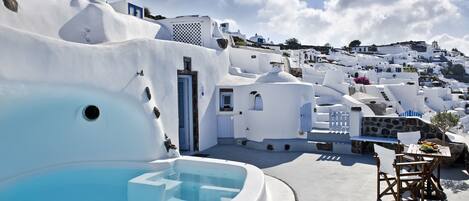 A white-washed building with a swimming pool and outdoor seating.