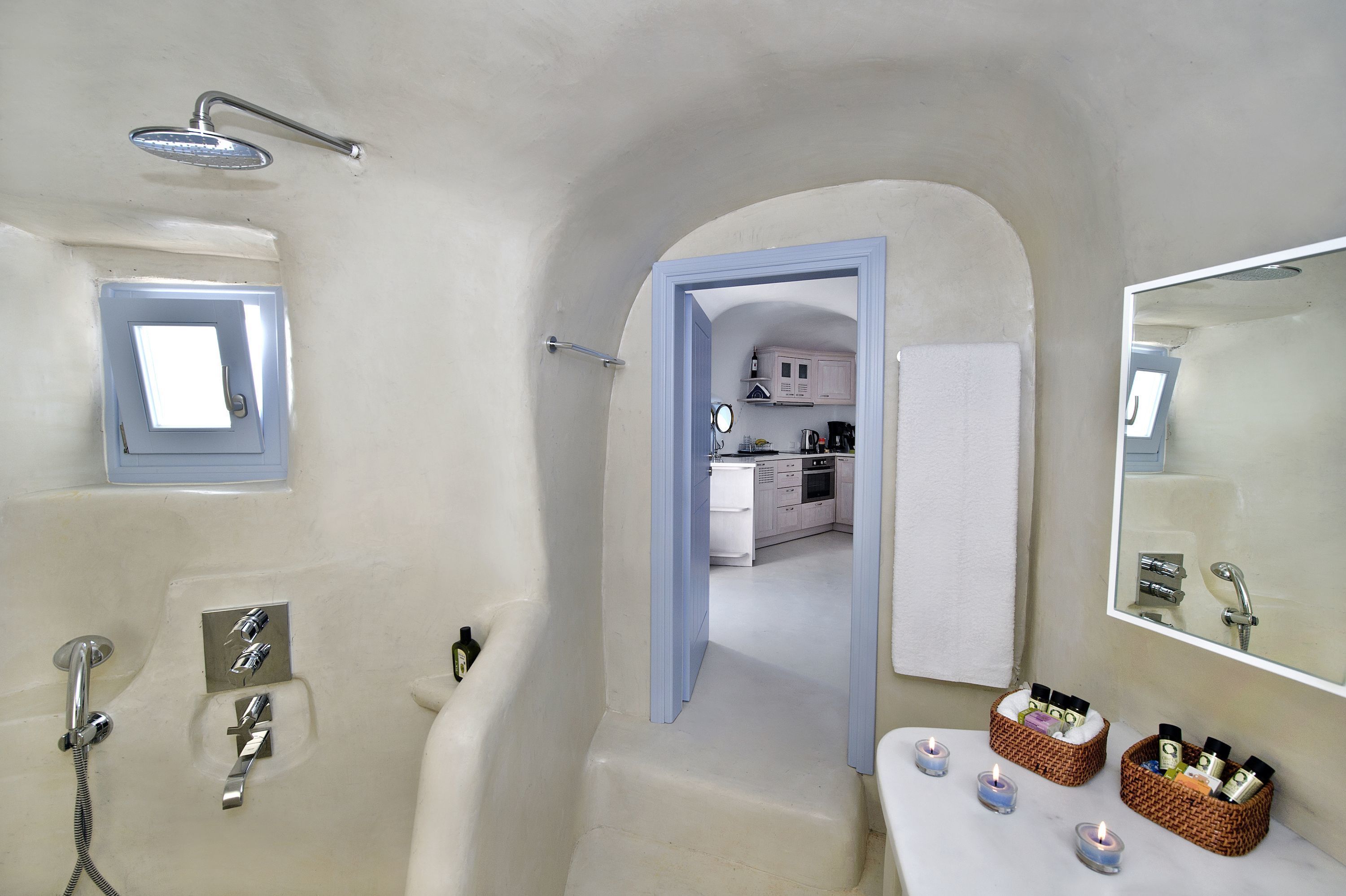 A bathroom with a bathtub, shower, and a mirror. There are two baskets with toiletries on the sink.