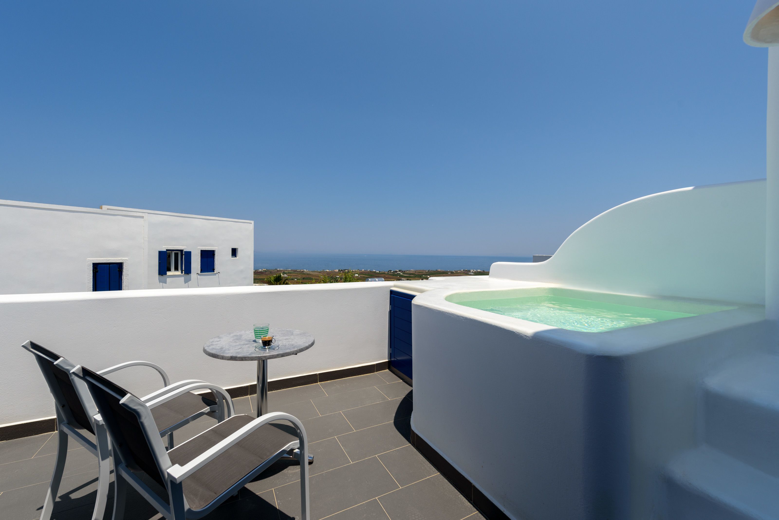 Una terraza en la azotea con un jacuzzi, una mesa con sillas y vistas al mar.