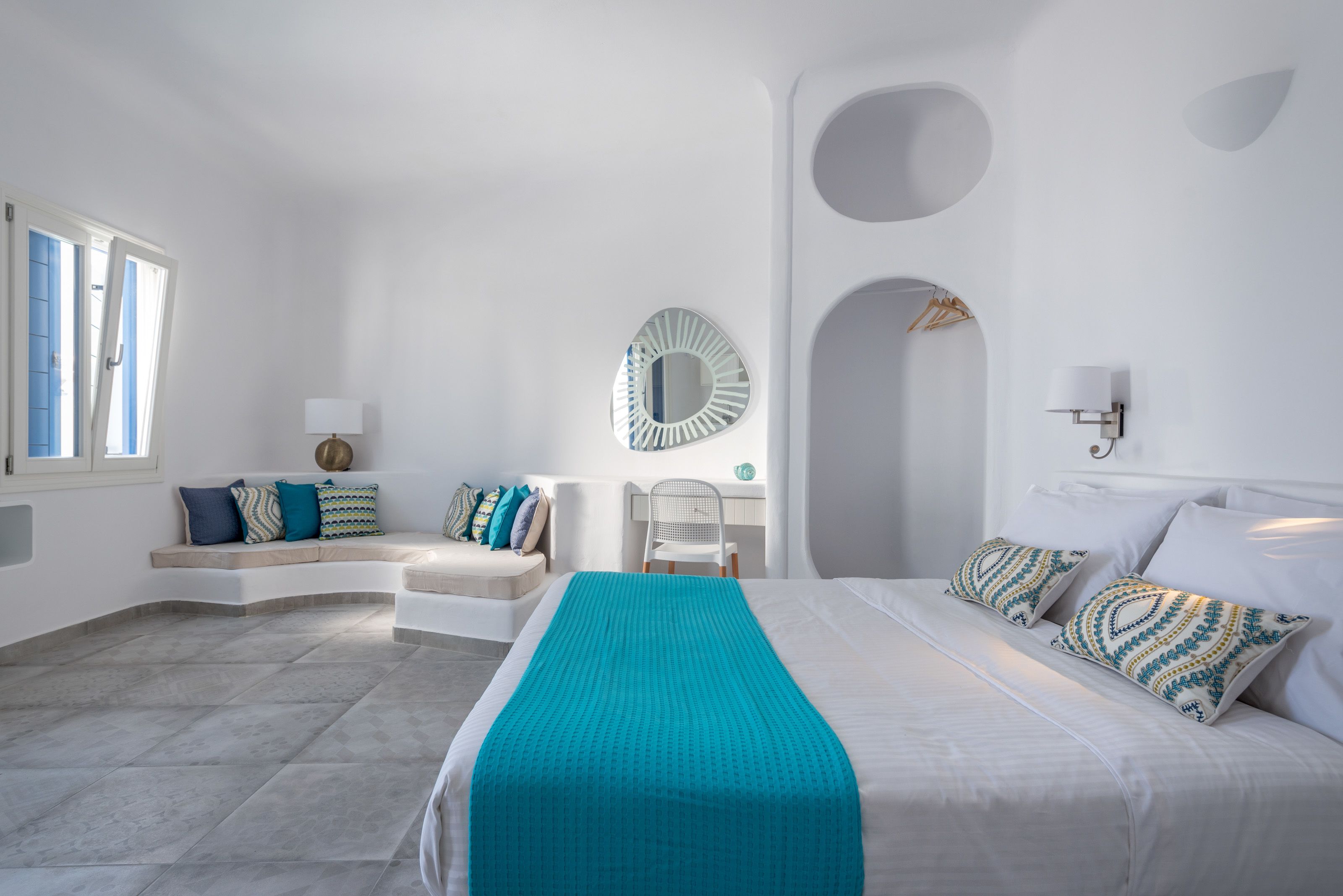 Un dormitorio moderno con cama, zona de estar, escritorio y espejo.