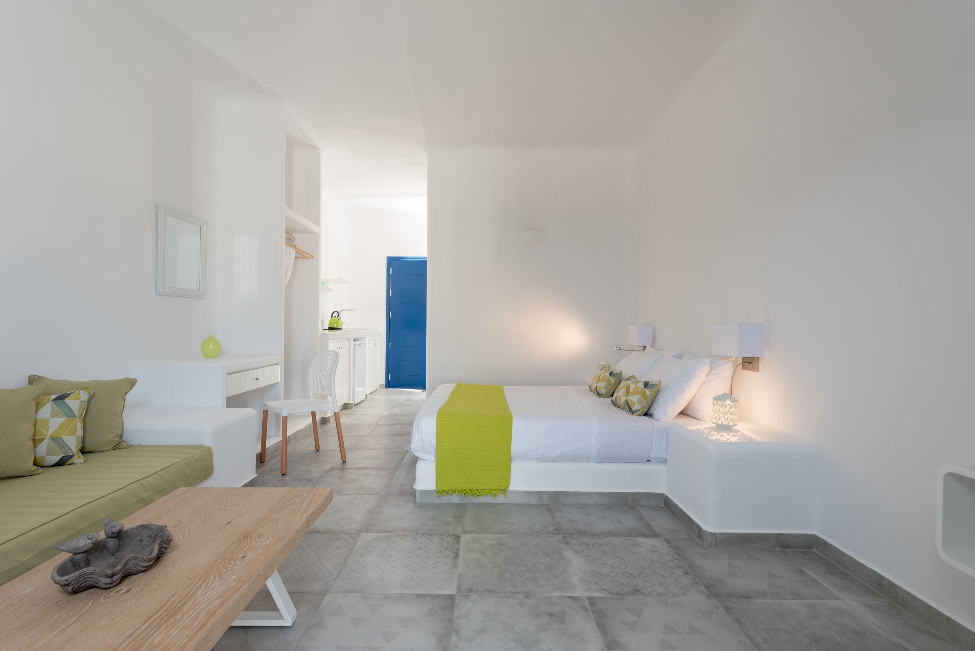 Una habitación de hotel moderna y minimalista con cama, sofá, escritorio y silla.