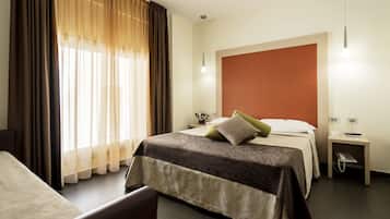 Une chambre d’hôtel avec un lit, une table de chevet avec une lampe et une fenêtre avec des rideaux.