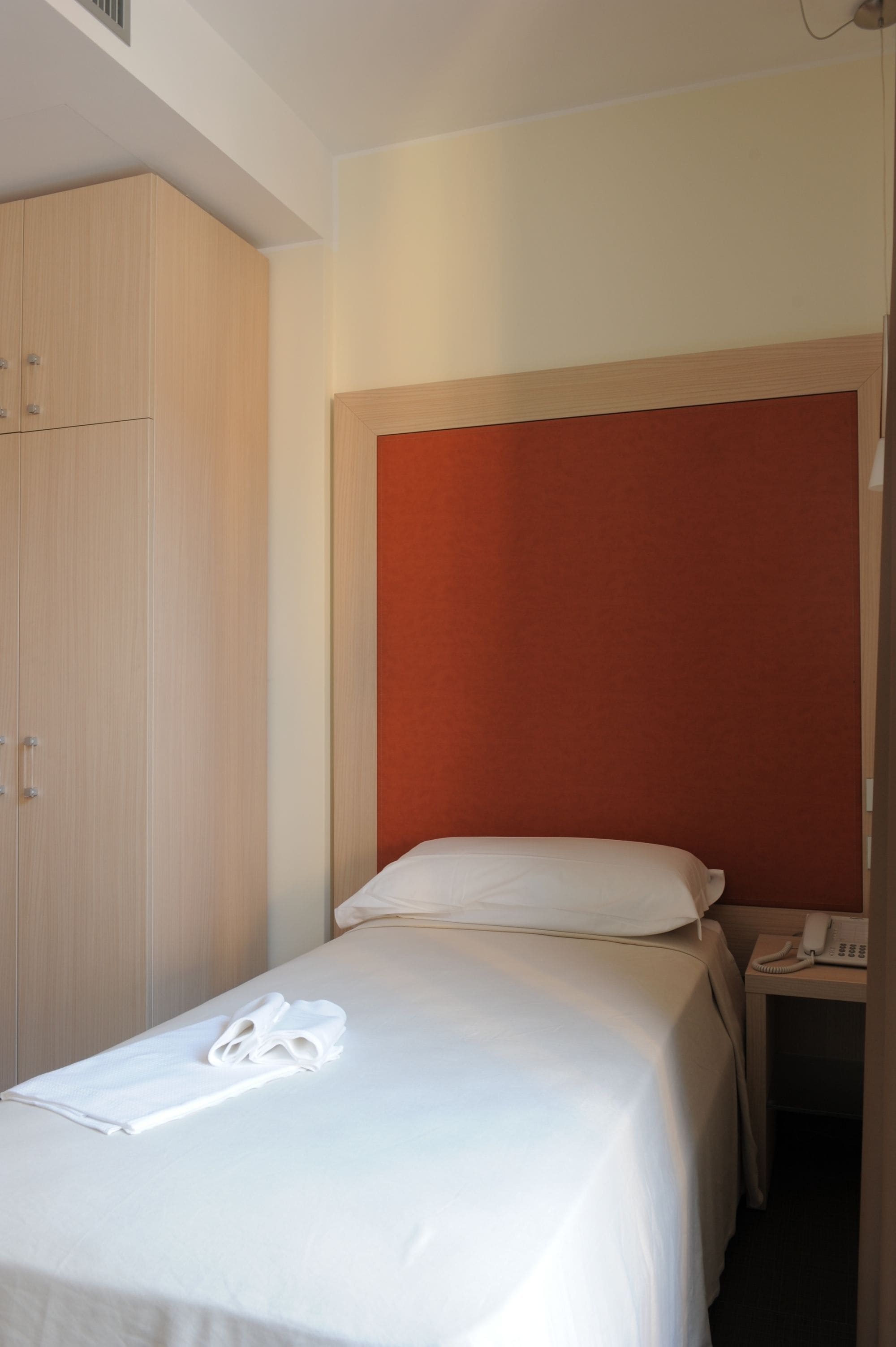 Une chambre d’hôtel avec un lit, une armoire et un téléphone.
