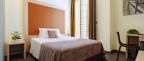 Une chambre d’hôtel bien aménagée, avec un grand lit, un bureau et une chaise.