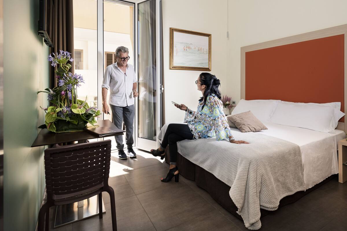 A hotel room with a bed, a desk, and a chair.