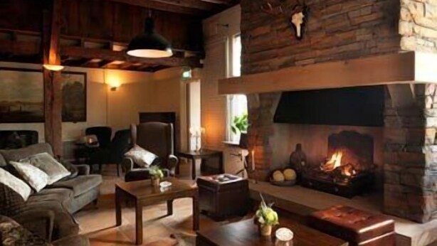 Een gezellige woonkamer met een stenen openhaard, houten meubels en een comfortabele zithoek.