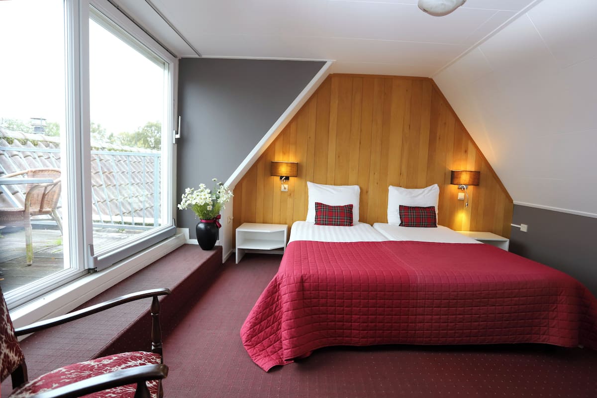 Une chambre avec un grand lit, deux tables de chevet, une fenêtre et une vue sur l’extérieur.