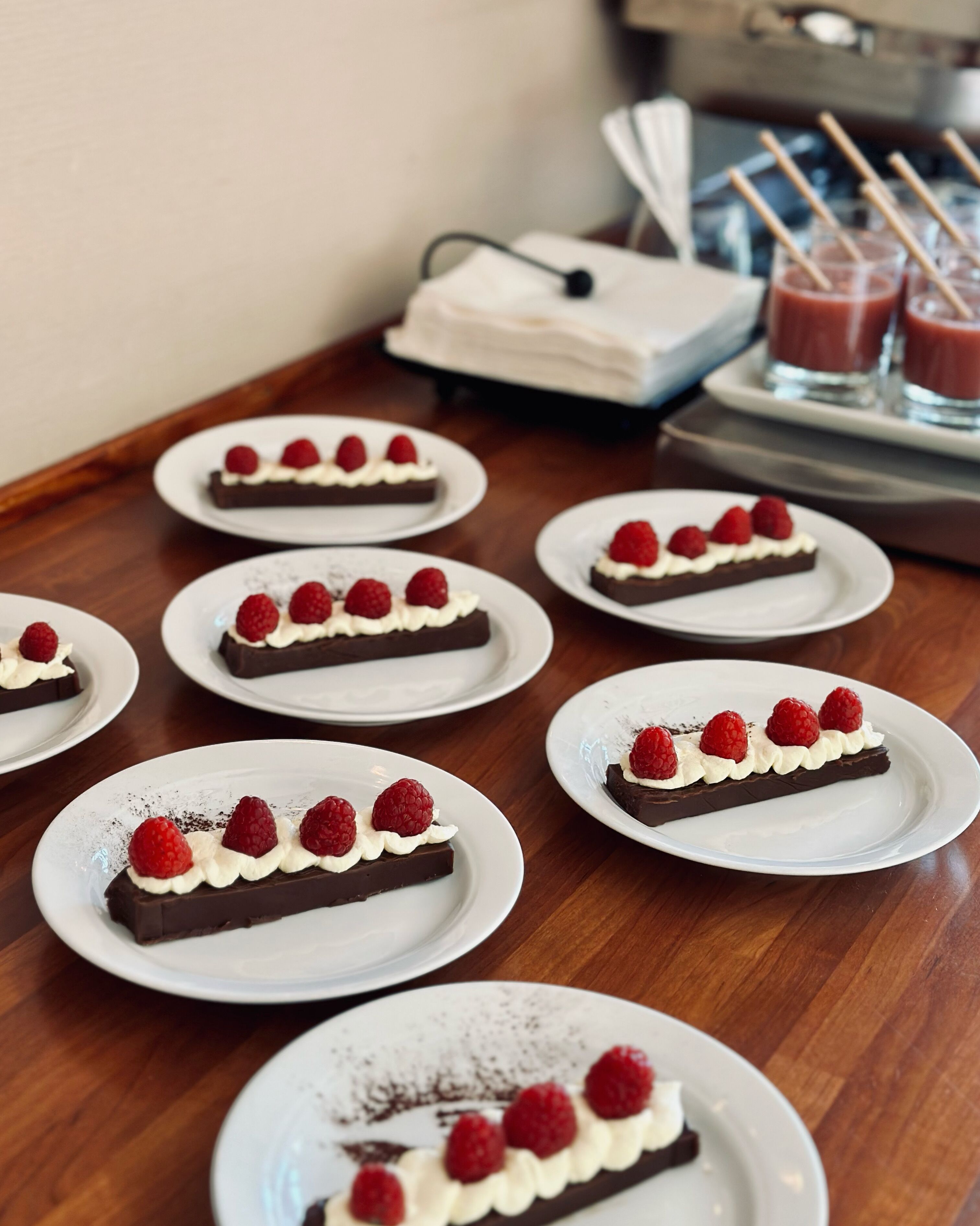 A table with multiple plates of dessert, each topped with chocolate and raspberries.